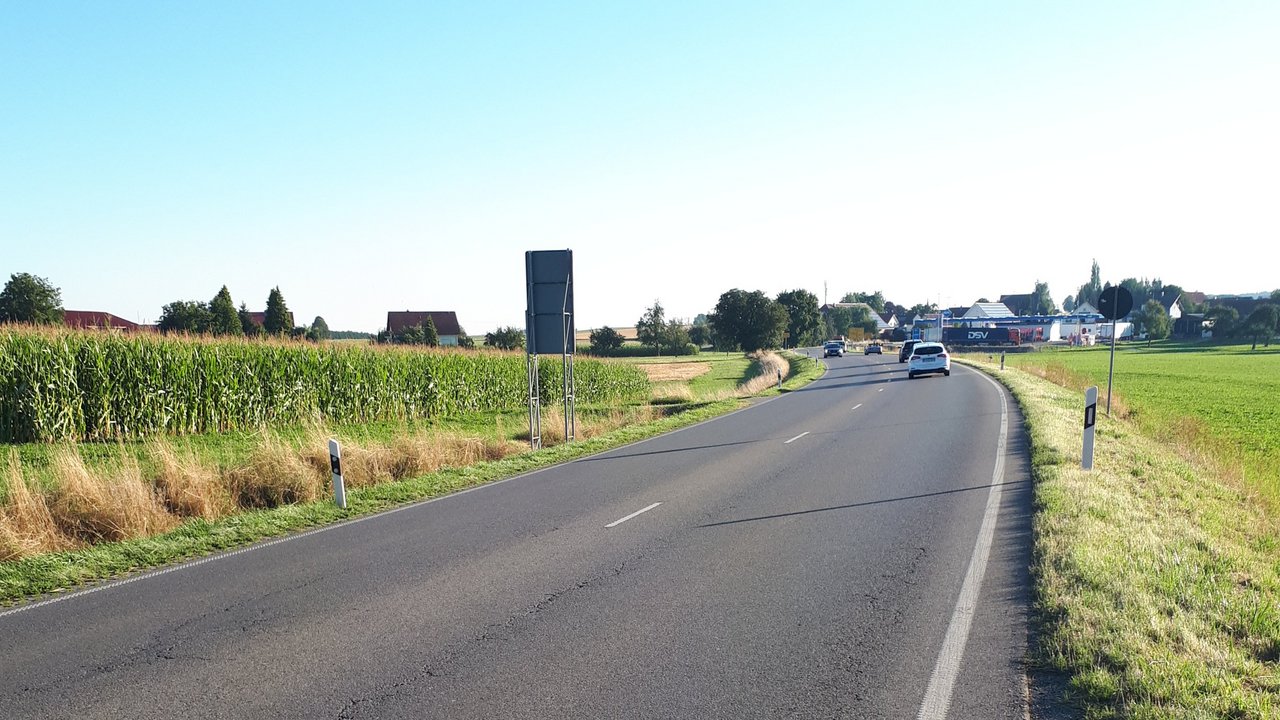 Das Foto zeigt die B 30 mit Blick in Richtung Enzisreute. Rechts und links sind Wiesen bzw. ein Feld zu sehen. neben der Straße 
