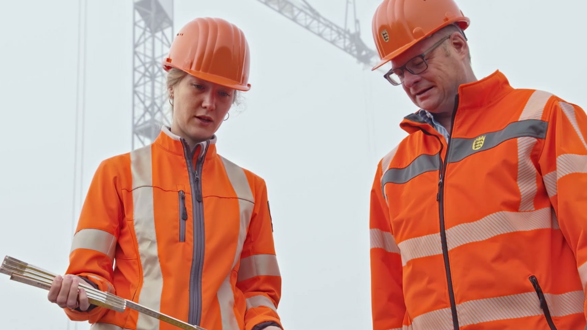 Zwei Kollegen aus der Straßenbauabteilung blicken auf einen Plan.