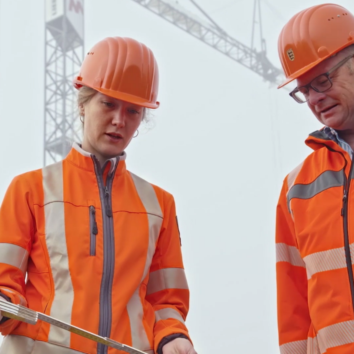 Zwei Kollegen aus der Straßenbauabteilung blicken auf einen Plan.