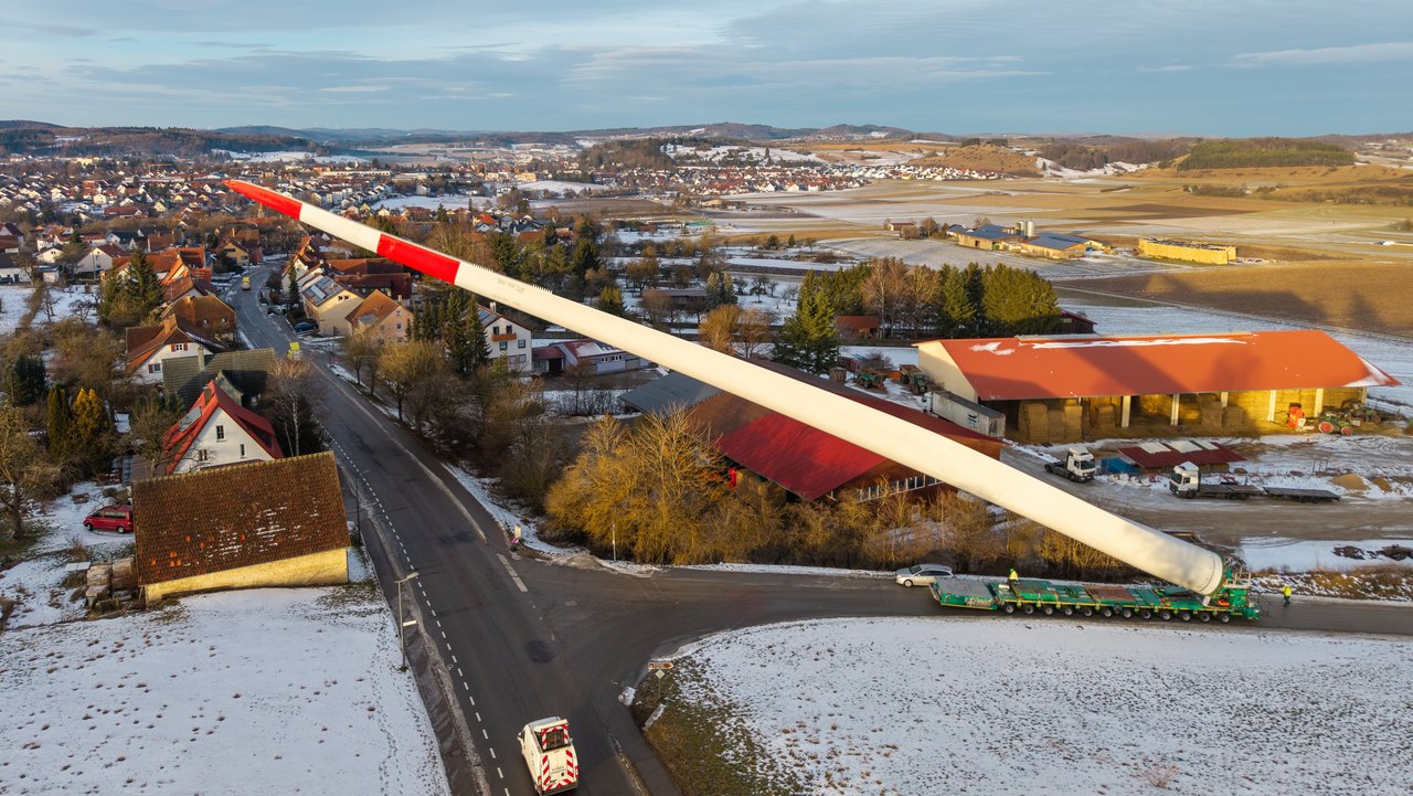 Blick von oben: Ein Schwerlasttransporter transportiert ein Rotorblatt durch enge Straßen in Gomadingen