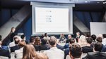 Das Foto zeigt ein Rundtischgespräch mit Publikum und eine große Leinwand