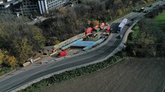 Ein Luftbild einer Baustelle. Über einem graben ist eine H-förmige Betonkonstruktion zu sehen. Neben der Baustelle verläuft eine Behelfsumfahrung.