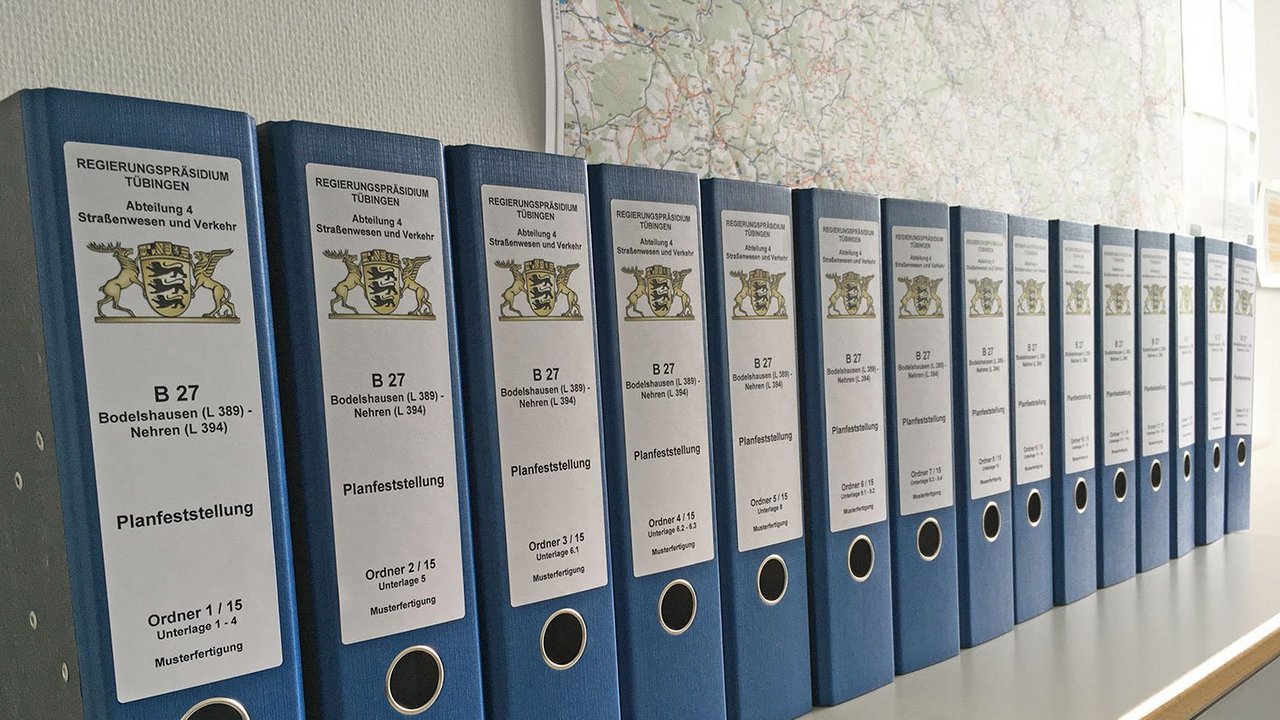 mehrere blaue Aktenordner stehen hintereinander in Reihe