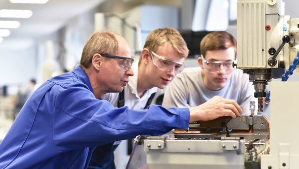 Gruppe junger Menschen in technischer Berufsausbildung mit Lehrer