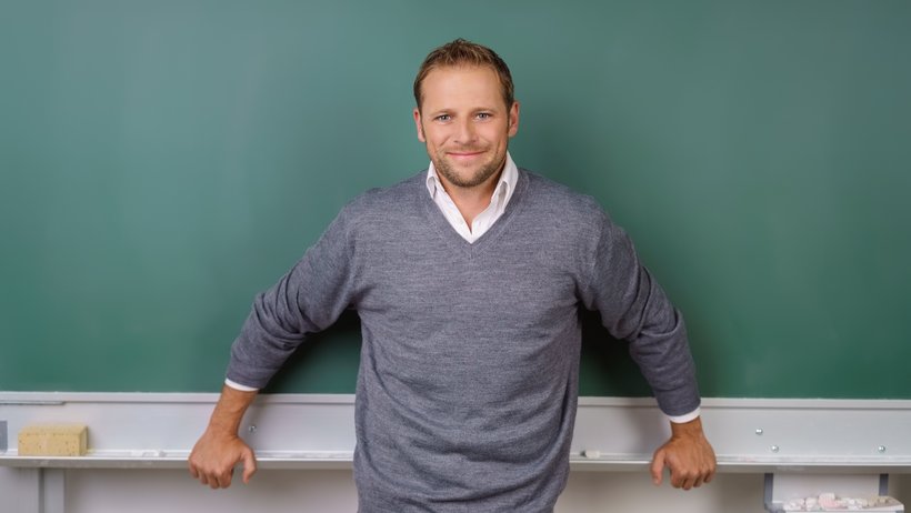 Lächelnder Lehrer vor der Tafel