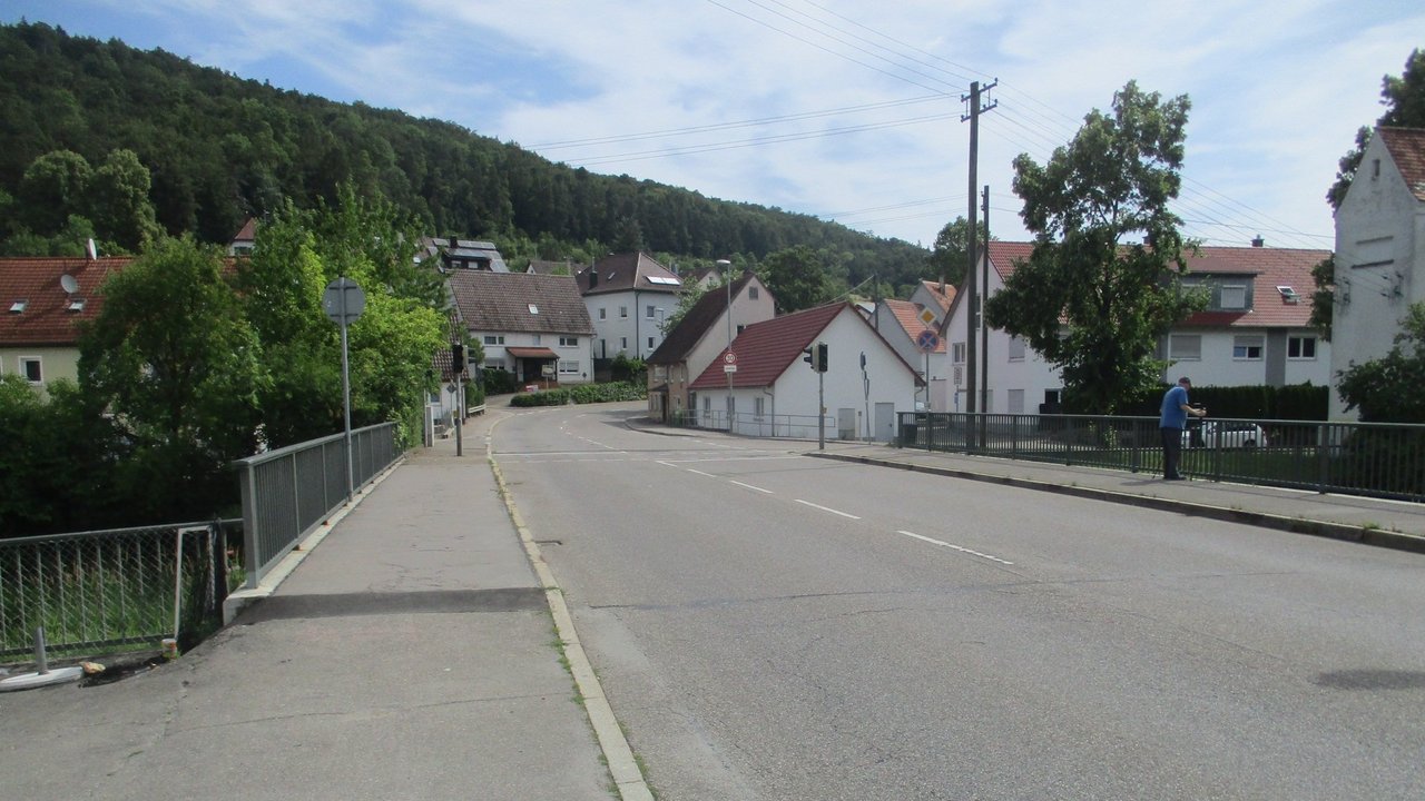 Das Foto zeigt die Ortsdurchfahrt von Gerhausen; mehrere Häuser und eine Brücke; im Hintergrund Wald