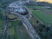 Luftbild einer Straßenbaustelle. Neben dem bestehenden Straßendamm ist Erde aufgeschüttet, wodurch der Straßendamm breiter wird. 