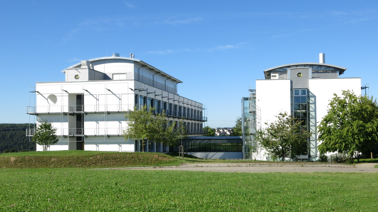 Zwei weiße, mehrgeschossige Gebäude auf einer grünen Wiese