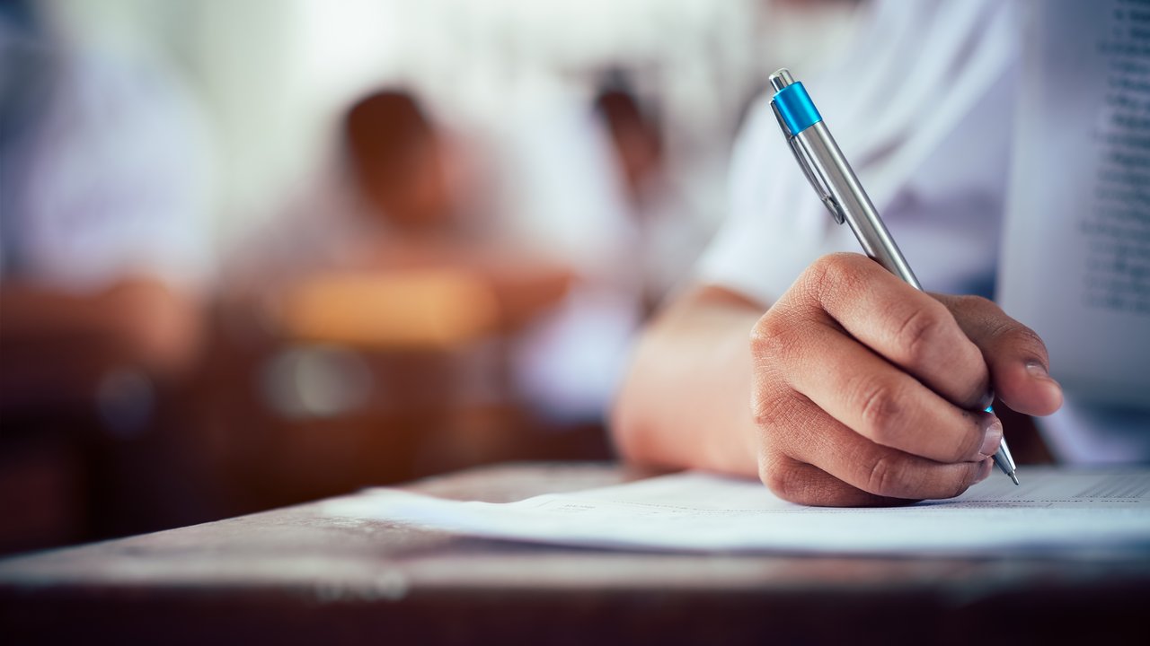Das Foto zeigt eine Person an einem Schreibtisch mit einem Stift in der Hand