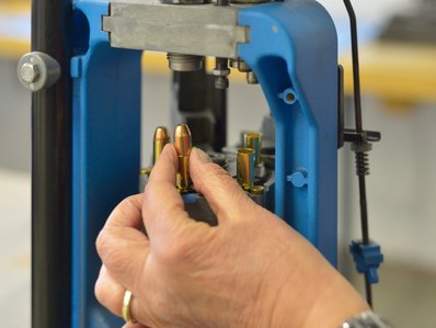 Munitionskontrolle; eine Hand hält eine Munition und stellt sie in das Gerät, welches die Kontrolle durchführt