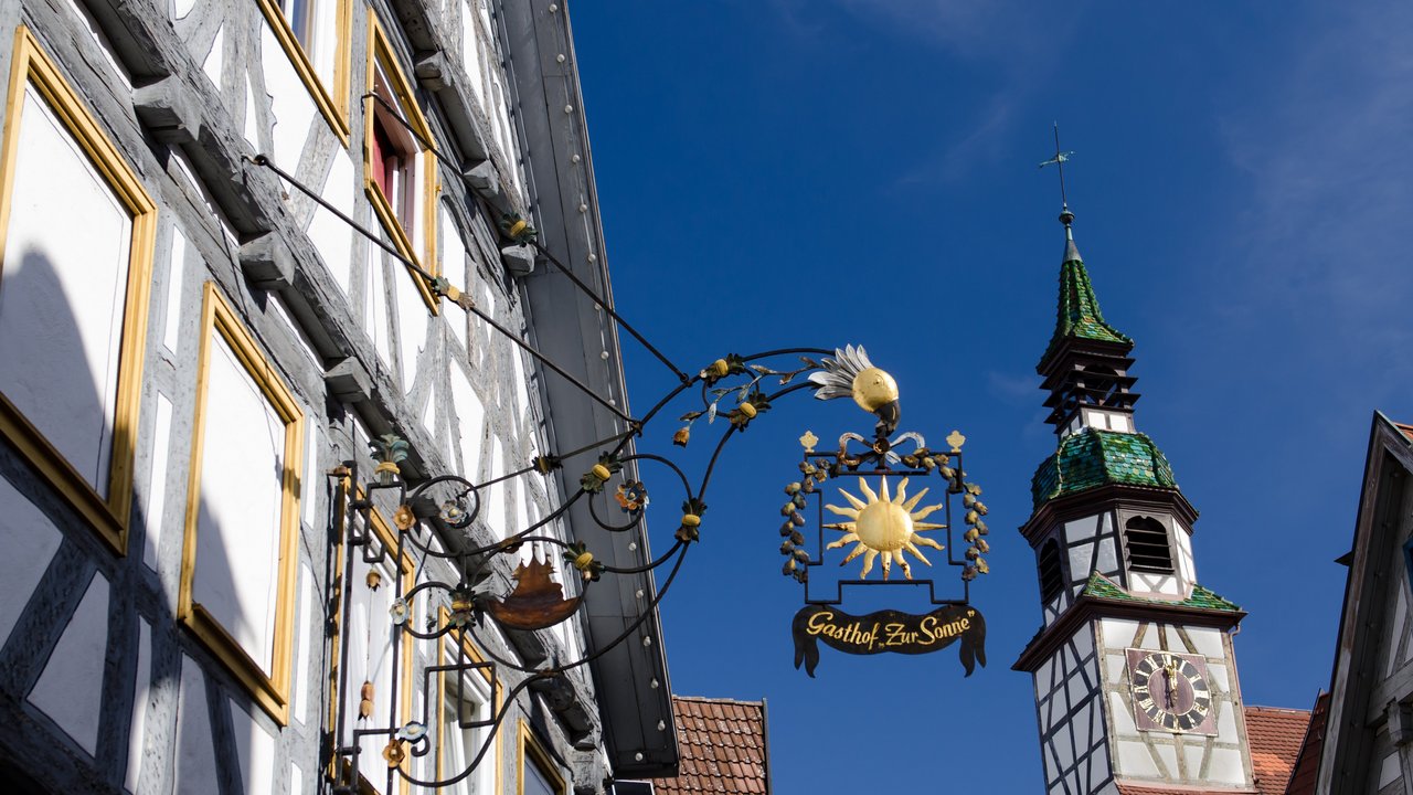 Das Bild zeigt ein Schild eines Gasthauses im Ortskern einer Stadt