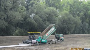 Einbau der Dichtungsschicht (Sandunterlage und Bentonitmatten) mit einem Asphaltfertiger