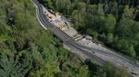 Luftbild einer Brückenbaustelle. Neben der Stelle, an der an beiden Ufern an der neuen Brücke gearbeitet wird, führt die Straße über eine Behelfsbrücke.
