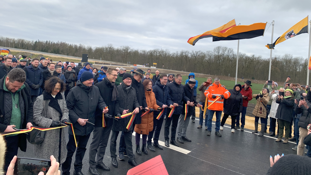 Besucherinnen und Besucher der Verkehrsfreigabe Querspange Erbach schauen den Verreterinnen und Vertretern aus Politik, verwaltung und Gesellschaft beim Durchschneiden des Bandes zu.
