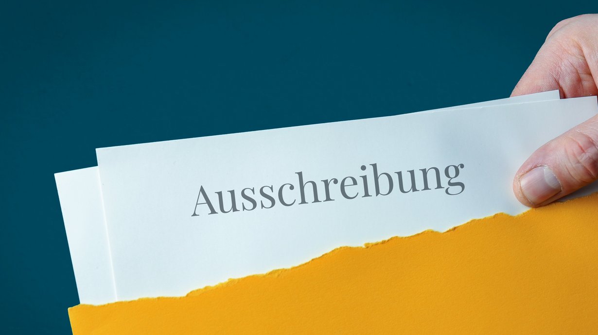 Öffentliche Ausschreibung. Brief-Umschlag (gelb) offnen. Hand zieht Dokument heraus