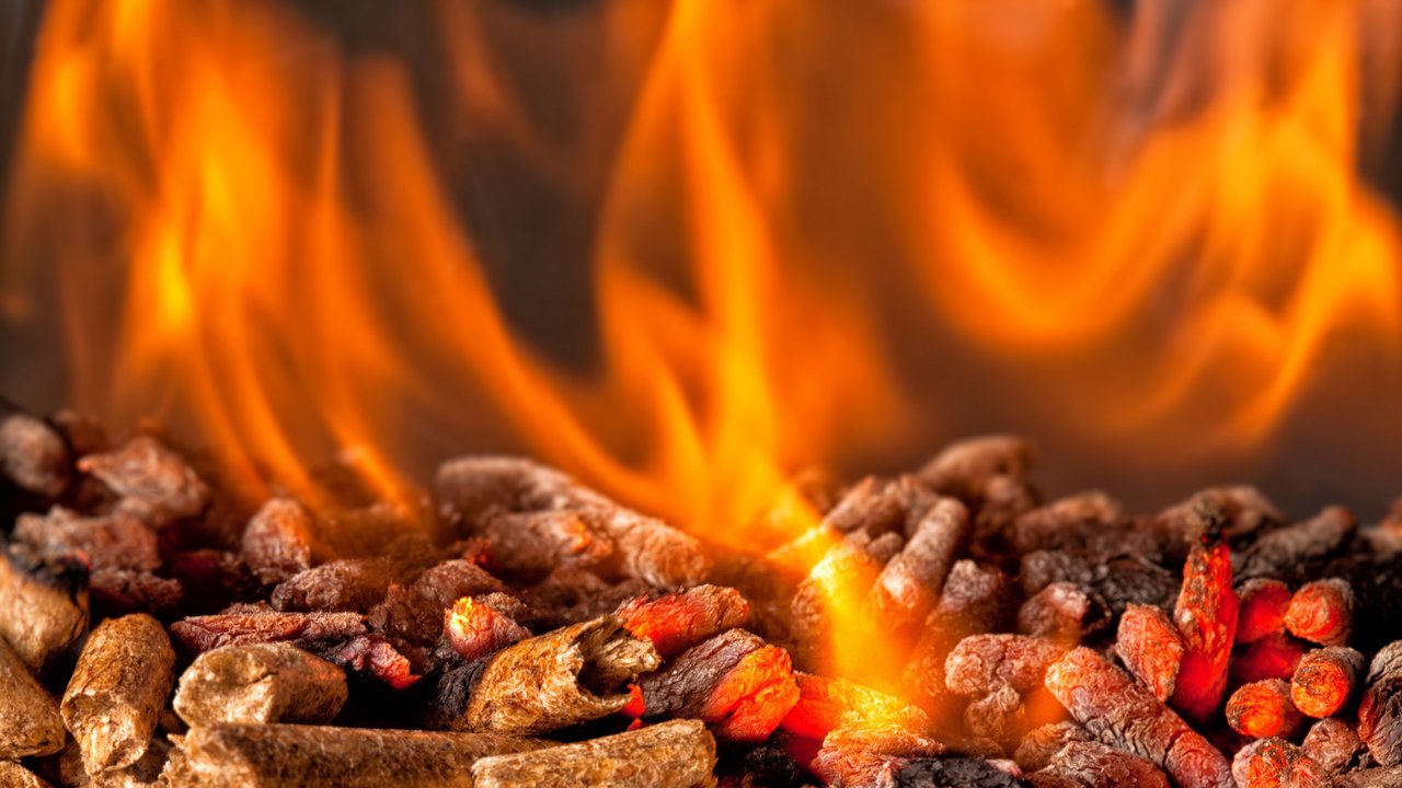 Das Bild zeigt brennende Holzpellets mit orangeroter Flamme